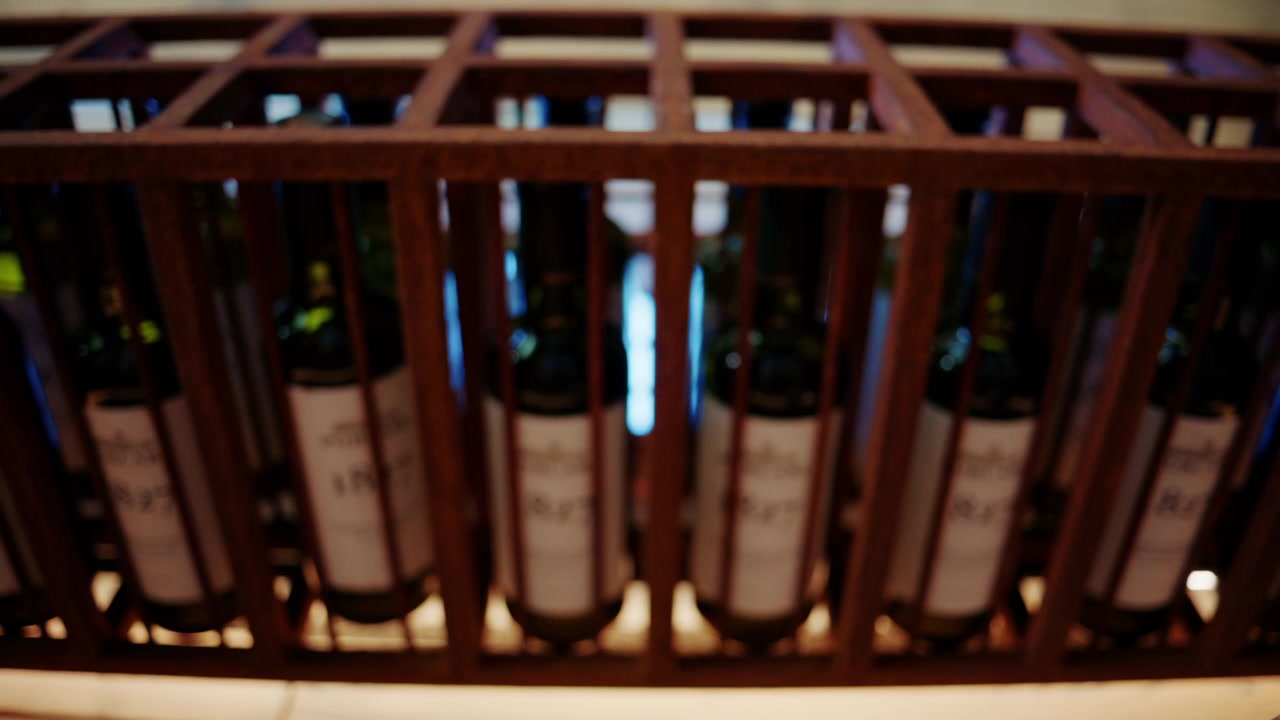 File di bottiglie di vino conservate in una scaffalatura in legno per cantina.