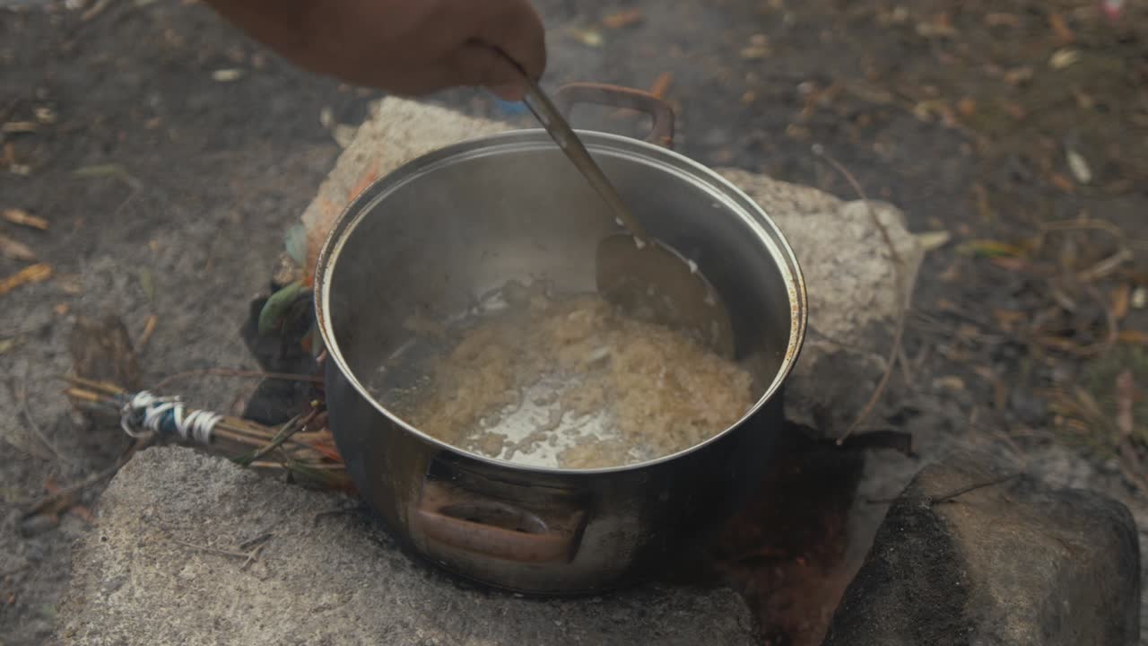 revolviendo olla de arroz cocinando sobre fuego campamento de refugiados de moria