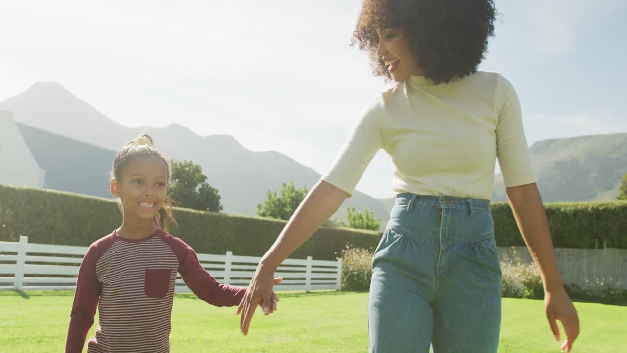 Video of happy african american mother and daughter spending time together in the garden