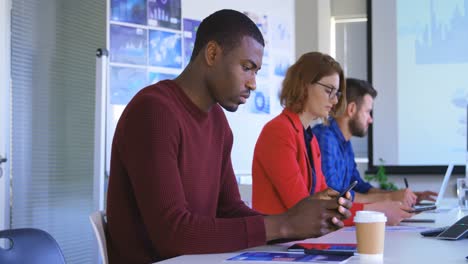 Side-view-of-young-mixed-race-business-team-working-in-conference-room-at-office-4k