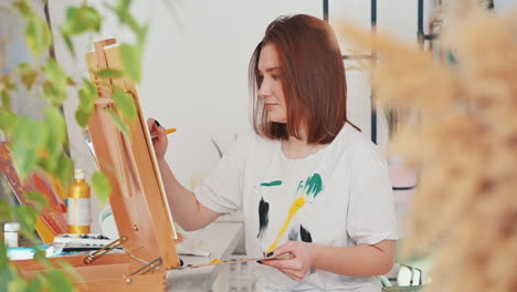 a red haired young woman artist painting a frame