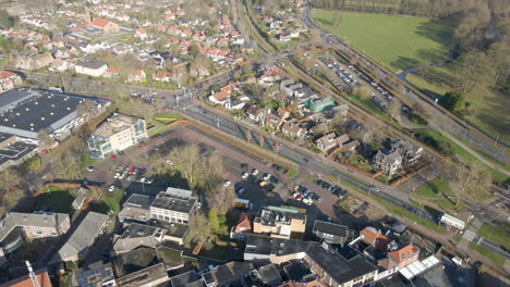 Aerial-of-small-parking-lots-at-the-edge-of-idyllic-town-with-traffic-driving-over-busy-streets