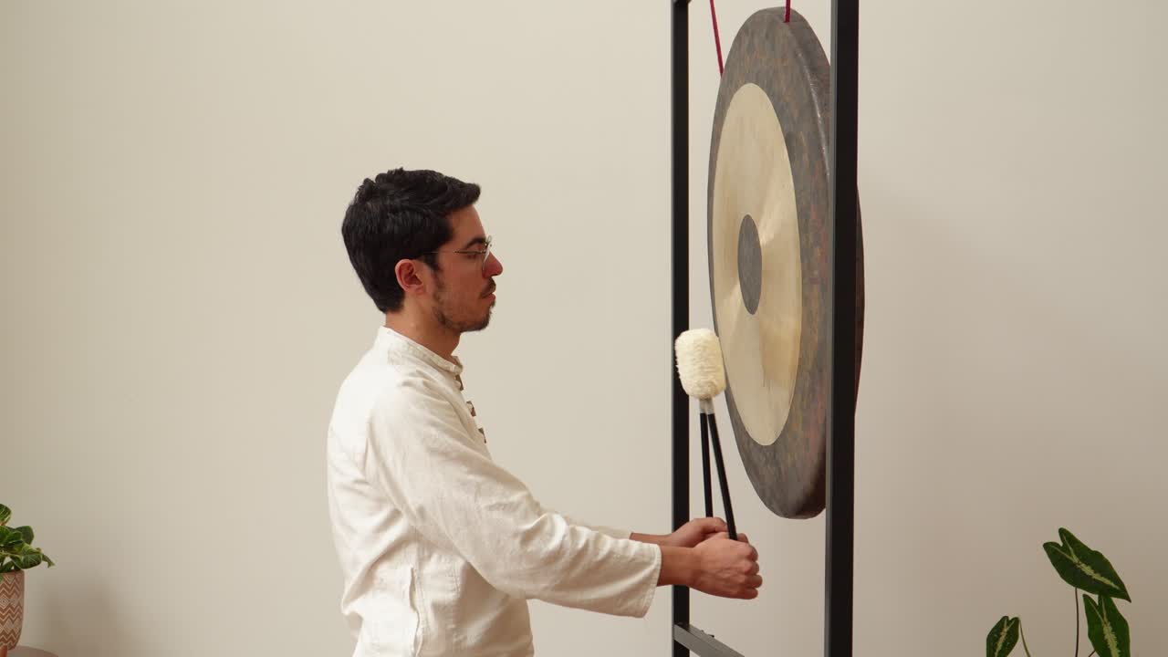 Latin musician performing on gong with roller coaster in background