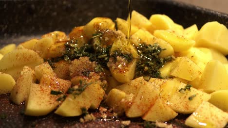 seasoning the cutted potatoes with aromatic herbs, sage, rosemary, hot spices and italian extra virgin olive oil - close up footage