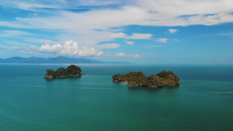 barco pasando por dos pequeñas islas montañosas, pulau gasing y pulau pasir