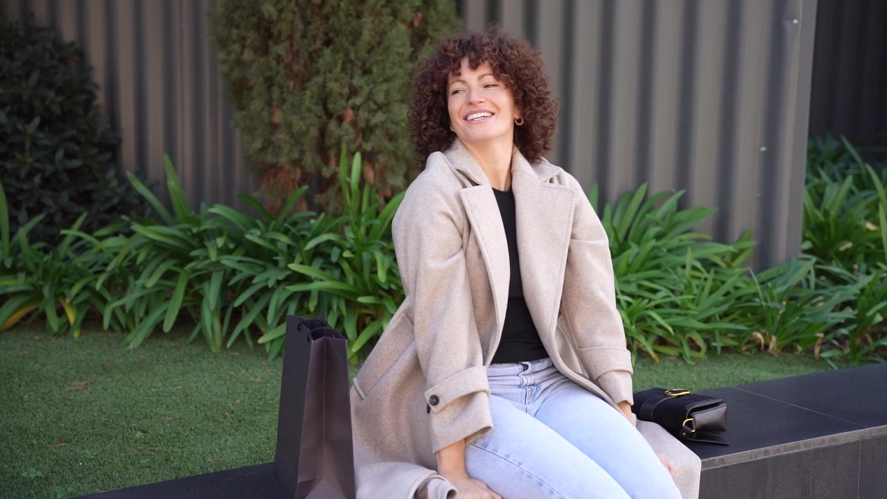 Una mujer alegre celebrando al aire libre, adoptando un sentido de la moda elegante y actual.