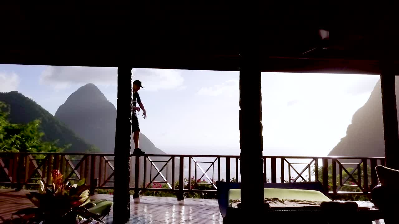 한 남자가 세인트 루시아 캐리비안의 고급 호텔 객실 발코니에서 걷고 춤을 춥니다.
