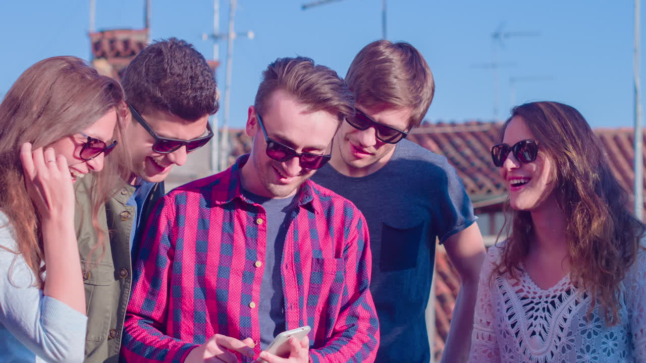 amigos en un techo usando un teléfono inteligente