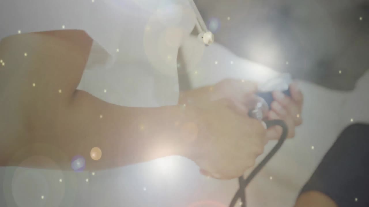 Animazione digitale di punti luminosi incandescenti su sfondo di una dottoressa che misura la pressione sanguigna di un paziente