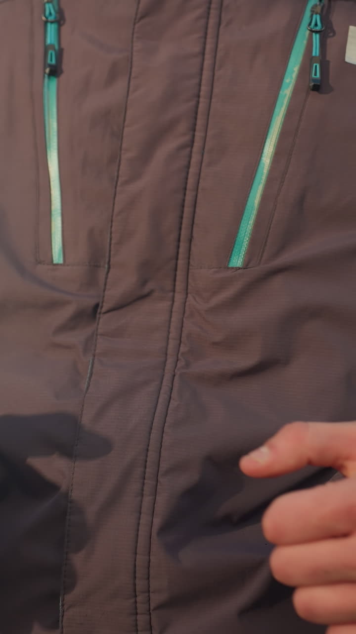 Close-up of man jogging outdoors in jacket, showcasing arm motion and fitness gear, emphasizing dynamic movement, determination, and active lifestyle against blurred urban backdrop