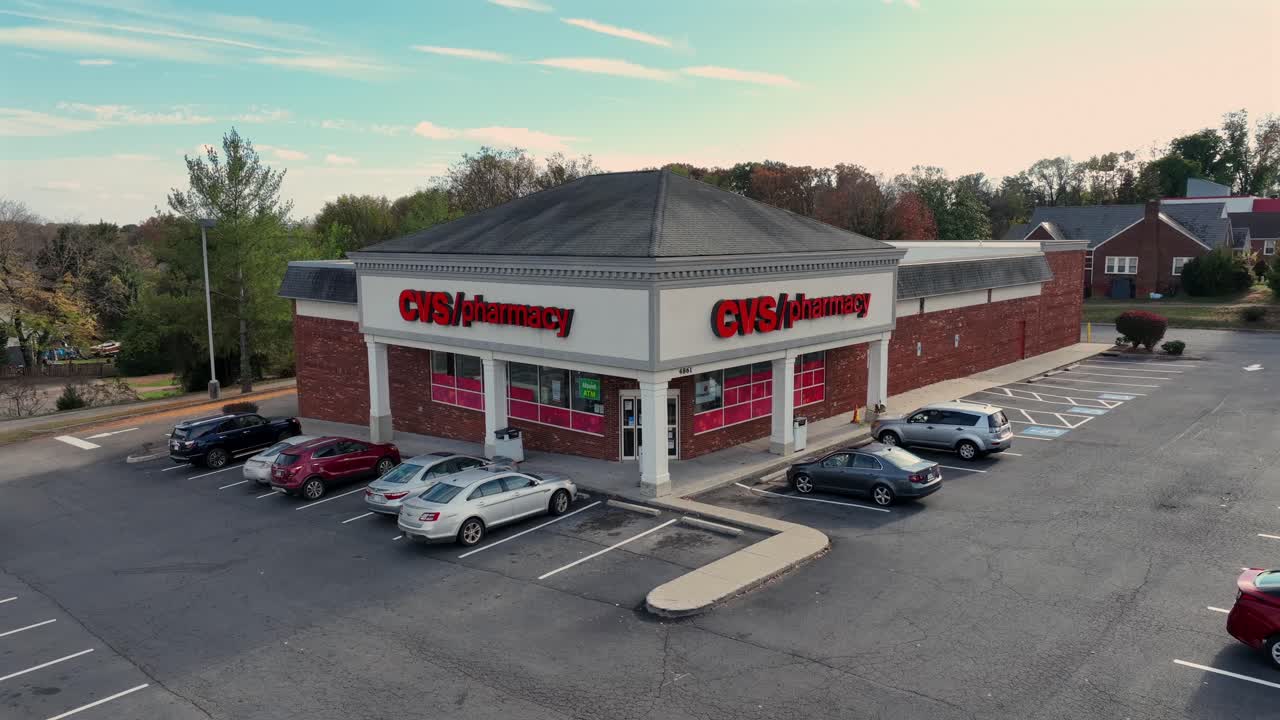 Aerial approaching shot CVS pharmacy store with parking cars in USA. Sunny day in autumn season. Sunny day in suburb district.