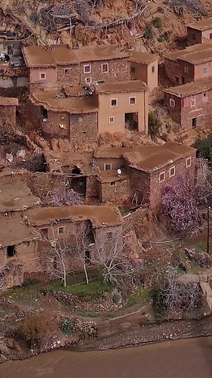 Vista aerea di case tradizionali in un villaggio marocchino lungo un fiume.