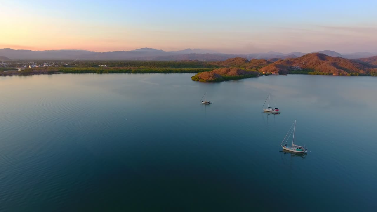 antena voladora hacia adelante con vistas a veleros anclados en una bahía tranquila