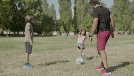 padre con discapacidad, hijo e hija pasando la pelota el uno al otro