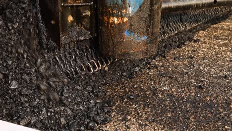 asphalt paver machine working during the day, close-up shot. road construction