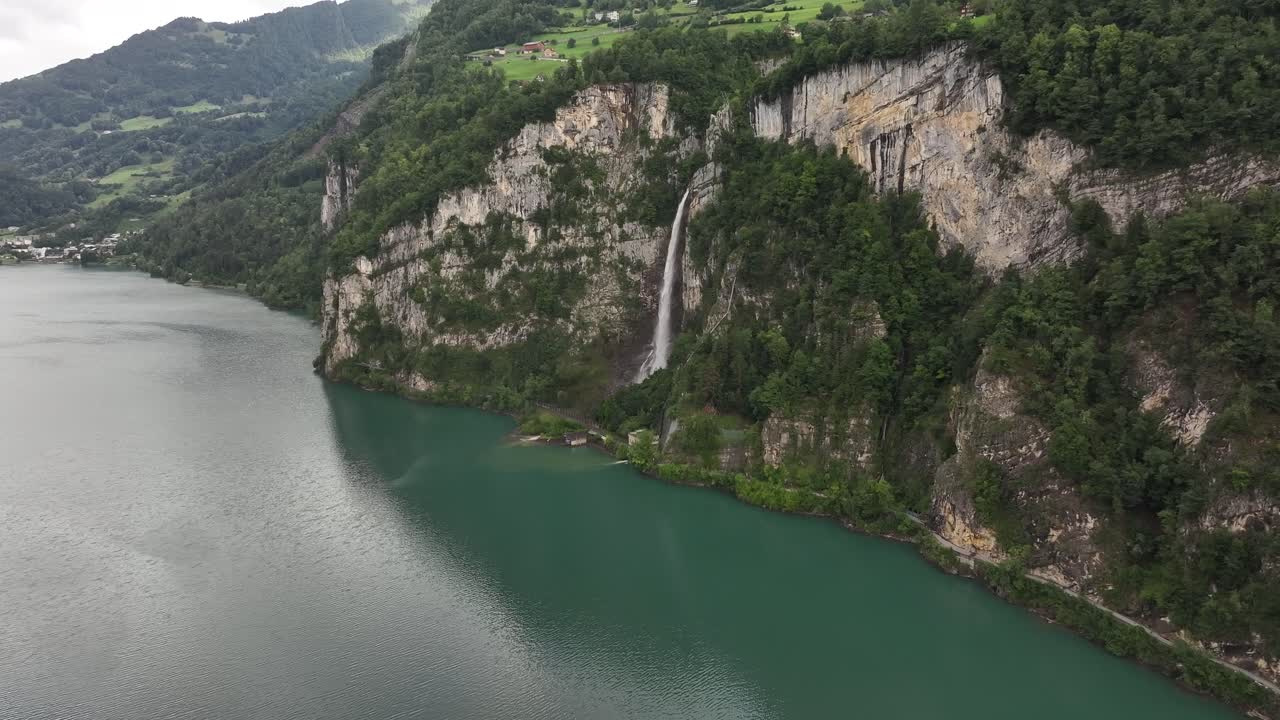 Walensee lake with Muslen waterfall flowing from cliffs on a summer day in Switzerland