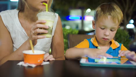 mother and son with pad in cafe