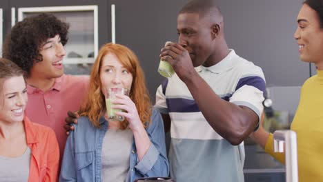 happy group of diverse friends preparing healthy drink in kitchen together