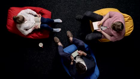 three workers are sitting on poufs and relaxing, office concept, communication concept