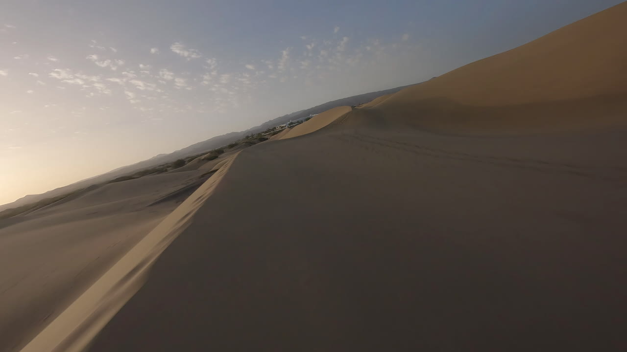 un dron aéreo rápido fpv vuela sobre las dunas de arena del desierto en el desierto de maspalomas