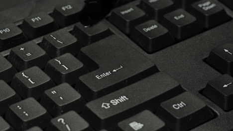 primer plano de un teclado de computadora negro con un dedo en la tecla de entrada