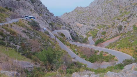 在西班牙的马洛卡 (mallorca) 冬天,一辆巴士在山上沿着一条狭窄的<unk>曲路转向,山上有茂密的森林