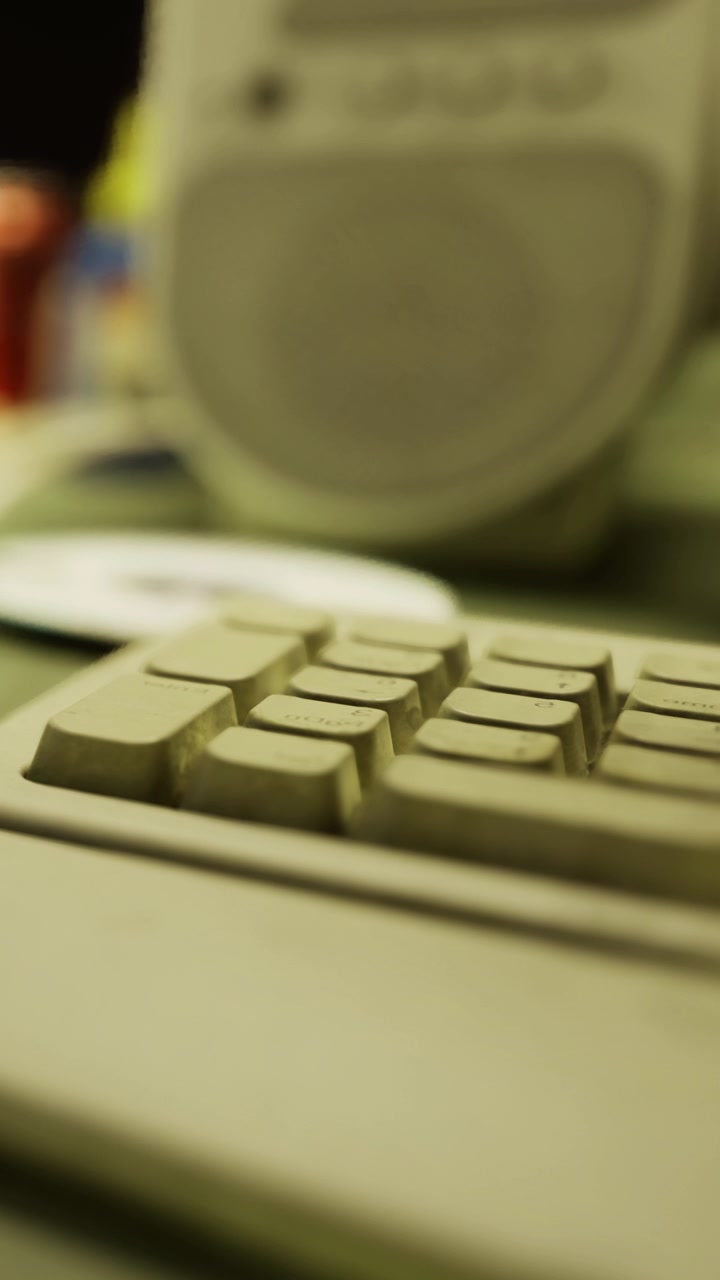 Old computer keyboard and speaker in a workspace setting with various items