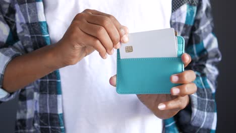 person putting credit card into a teal colored wallet