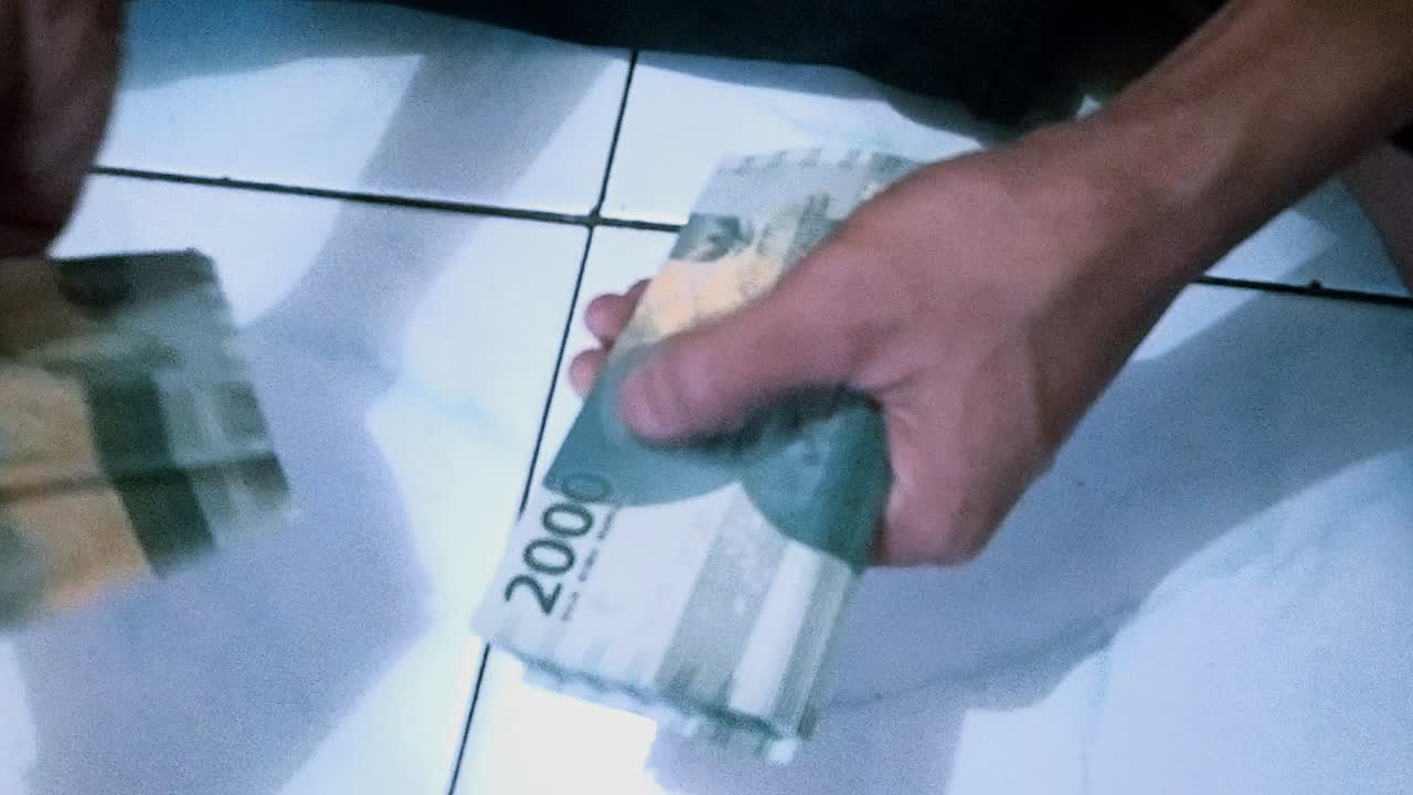 Liczenie dwóch tysięcy rupii indonezyjskimi pieniędzmi, wschodnioazjatycką ręką