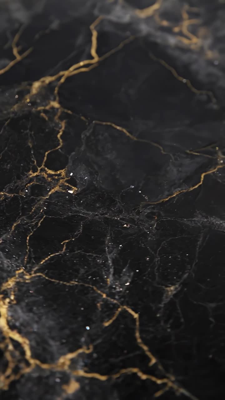 Video en primer plano de mármol negro con vetas doradas, capturado desde un ángulo cenital