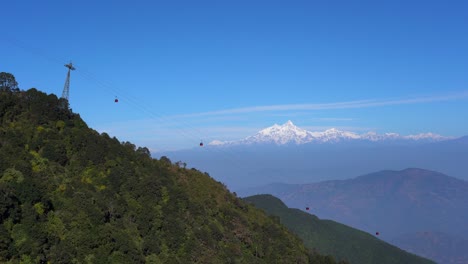 cable cars going up and down a mountain with the himalaya mountains in the background