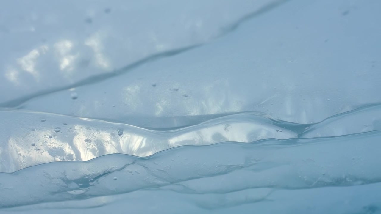 Luce cangiante che provoca bande di gel bluastre stratificate che si muovono lentamente in un primo piano macro, con bolle intrappolate
