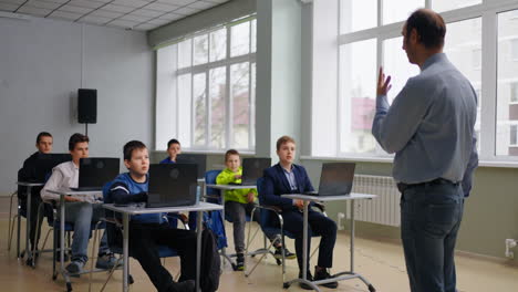 teacher leading a class in a modern classroom with laptops