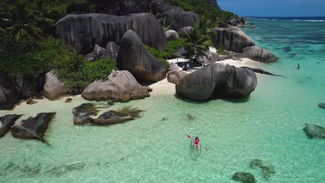 woman kayaking in clear bottom kayak at anse source d'argent beach in seychelles