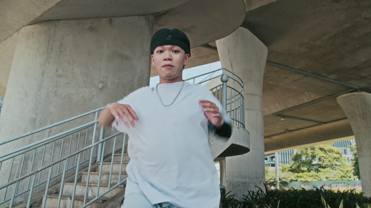 Ragazzo asiatico che guarda la fotocamera mentre si esercita nei movimenti di breakdance