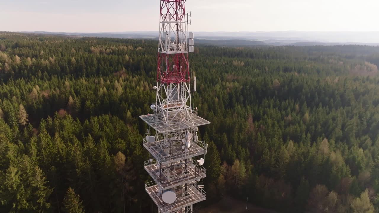 Drone view of a television tower providing data to the surrounding area. Close-up of the tower surrounded by forests
