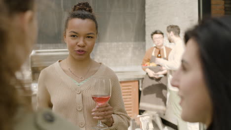 una hermosa mujer afroamericana bebiendo vino y divirtiéndose con sus amigos en una barbacoa