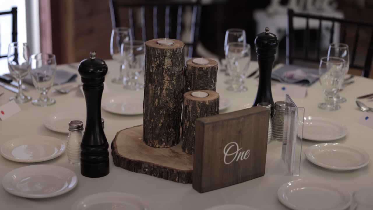 lugar de recepción de bodas decoración de mesa rústica y cubiertos, con platos blancos, velas de madera y centro de mesa y mantel blanco