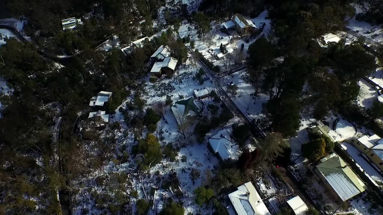 Experience the charm of Blue Mountains' roof houses blanketed in rare snow&mdash;a captivating aerial view showcasing the town's picturesque, snow-covered landscape