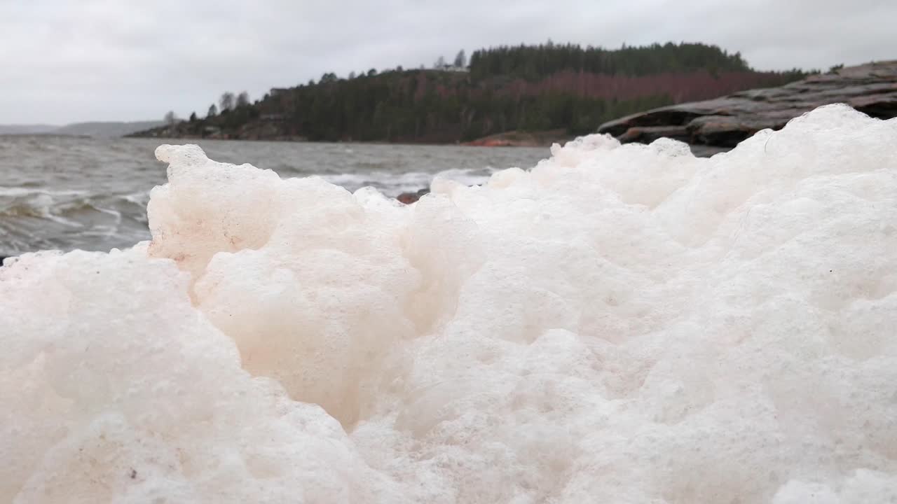 바다 거품은 바위가 많은 스웨덴 해안선의 흔들리는 물 위에 앉아 있습니다.
