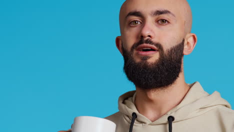 Middle-eastern-guy-drinking-cup-of-coffee-in-studio