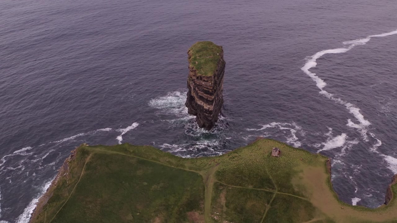 Panoramica aerea statica dall'alto che guarda giù verso la penisola di Downpatrick Head, con il faraglione Dun Briste e scogliere frastagliate.