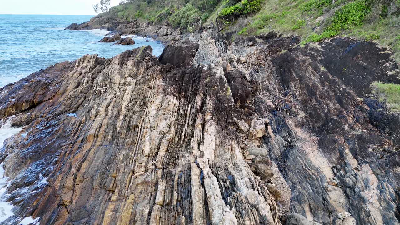 Aerial view of rugged coastline with waves crashing against rocks under natural daylight