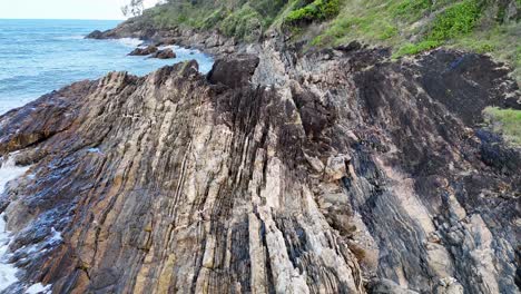 aerial view of rugged coastline with waves crashing against rocks under natural daylight