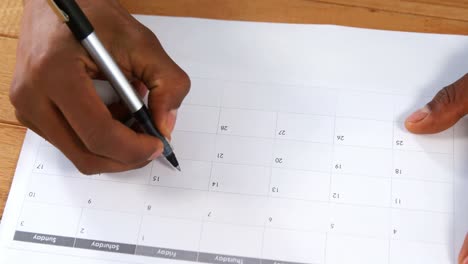 primer plano de un hombre marcando con un bolígrafo en un calendario