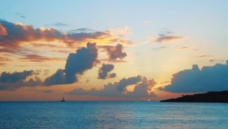 Sailboat-moving-through-Caribbean-Sea-during-orange-sunset,-SLOWMO