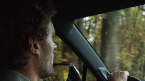 close-up shot, man driving, autumn forest reflecting in the side mirror