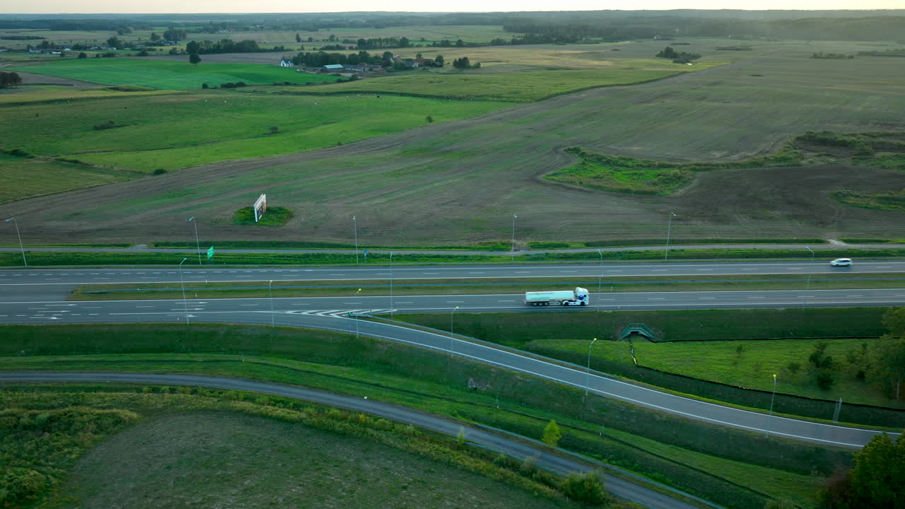 광활한 초록색 과 농지를 가로질러 가는 고속도로 폴란드의 공중 풍경, 저녁에 도로를 따라 이동하는 트럭과 자동차