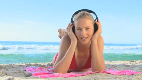 -Woman-lying-on-a-beach-listening-to-music