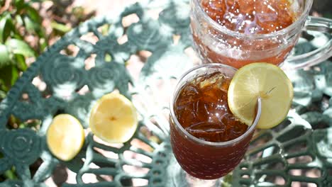 pouring tall glass of ice tea with lemon in outdoor summer garden wind blowing leaves shadows